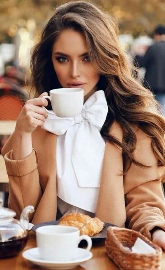 Красивая девушка пьет кофе у окна утром.