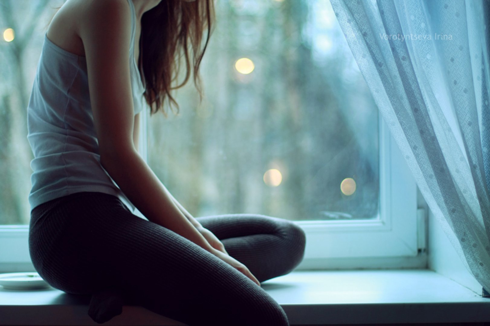 Фото силуэта с девушкой, сидящей спиной на столе у окна