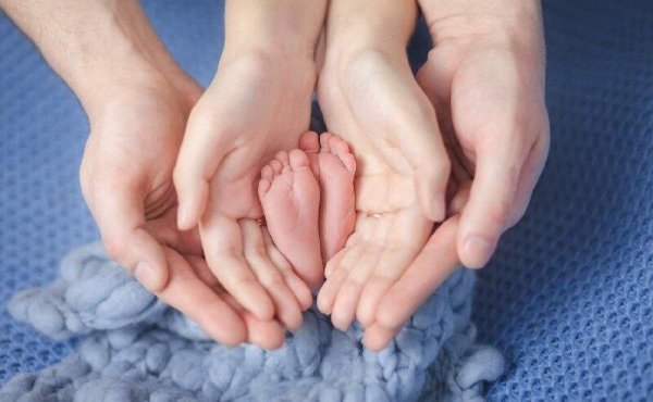 Ножки малыша в руках родителей