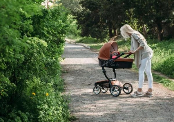 Мама с коляской гуляет в парке